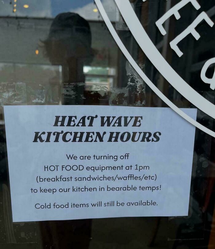 A sign on a glass door announces reduced kitchen hours due to the heatwave, affecting Europeans.
