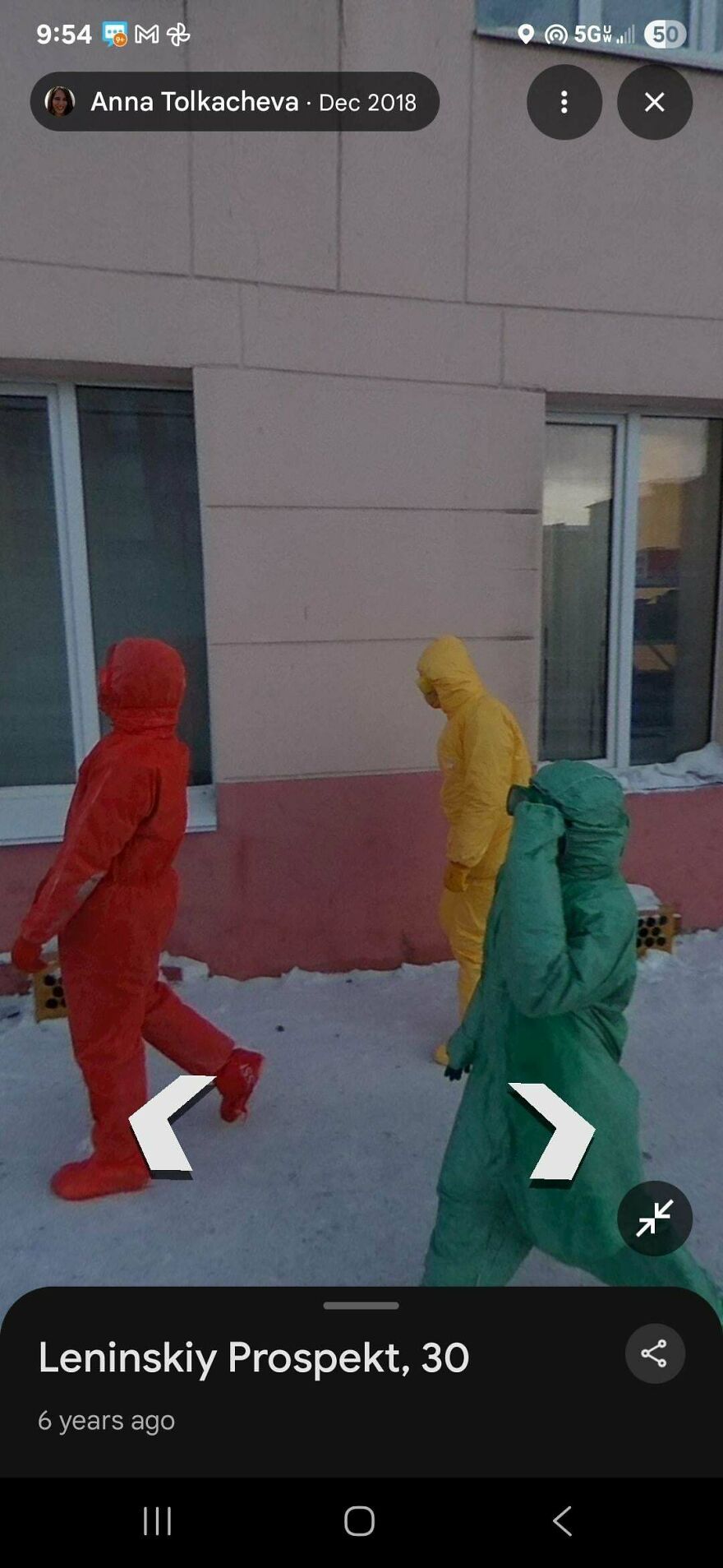 Three people in colorful hazmat suits walk in a funny Google Street View photo on a snowy street.