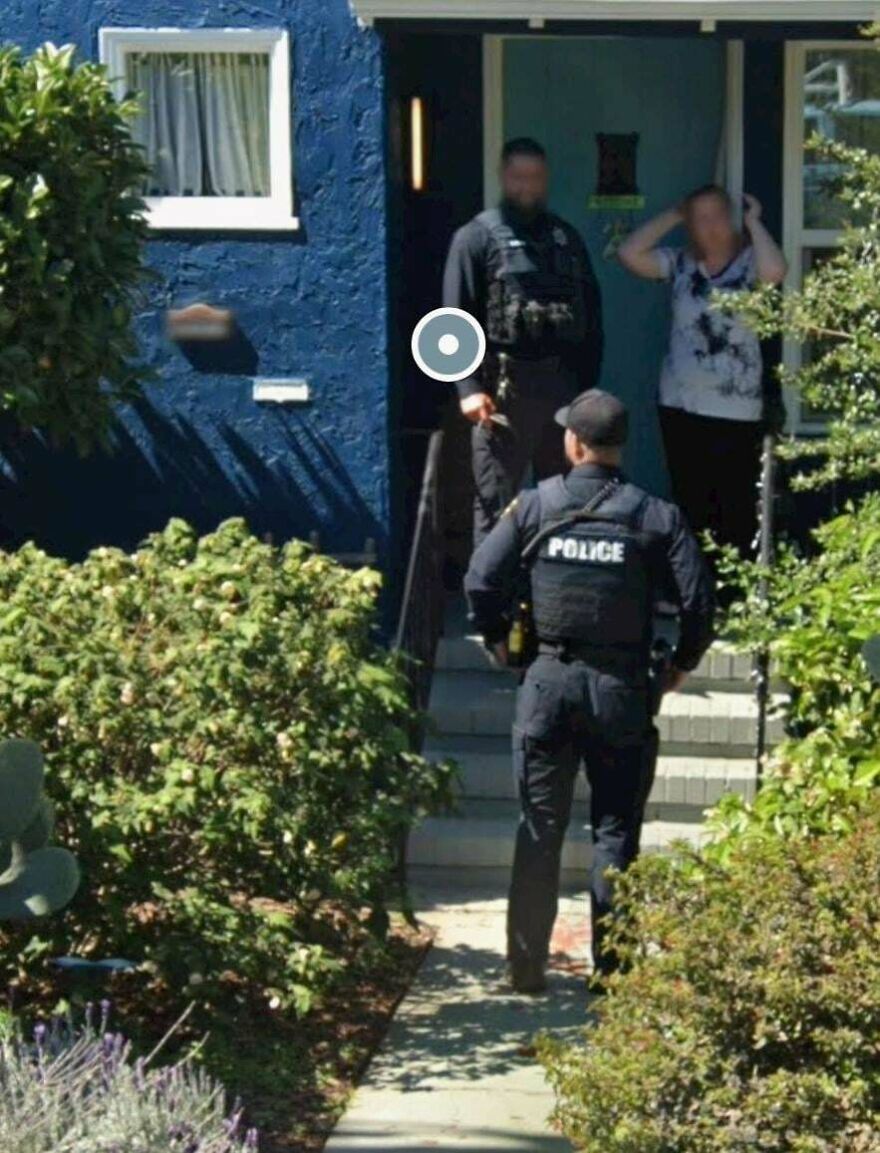 A bizarre Google Street View photo showing police officers at the entrance of a blue house, with a woman in distress.