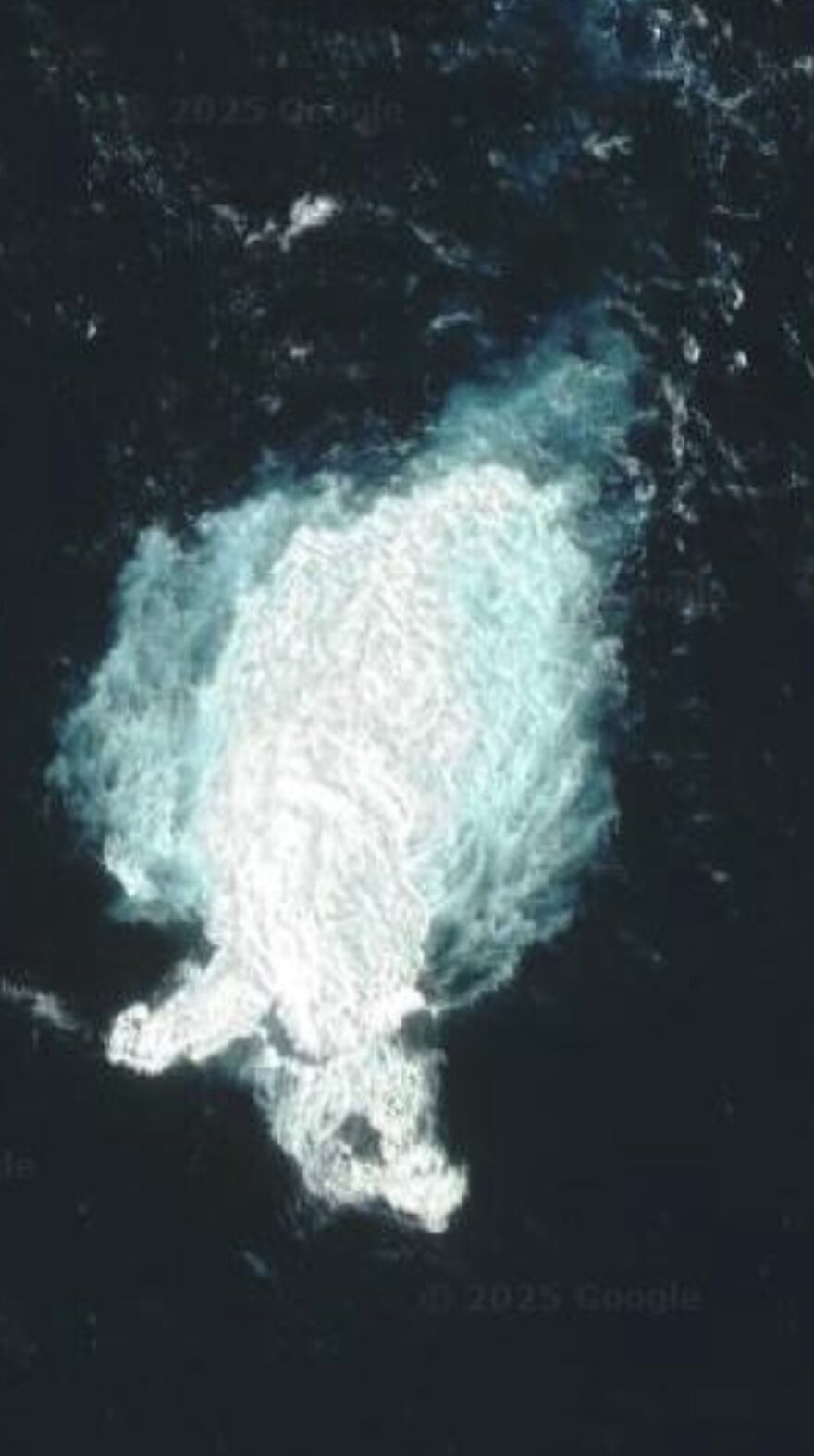 An aerial view from Google Street View showing a large, white, cloud-like shape in the dark ocean.