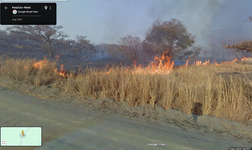 A field ablaze with fire, smoke rising, seen in a bizarre Google Street View image.