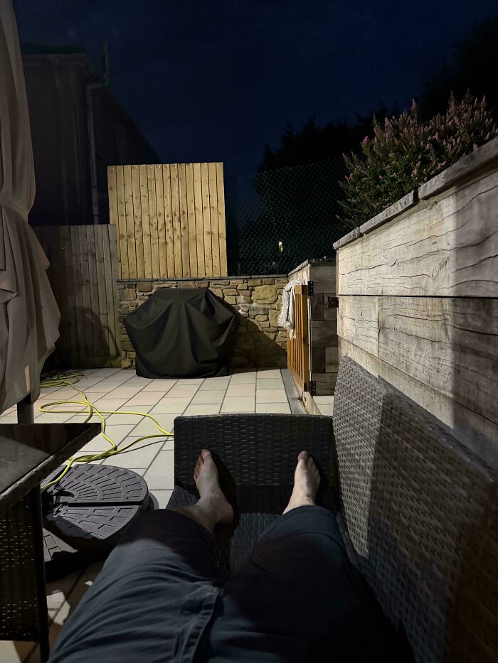 A person relaxing barefoot on an outdoor patio at night, trying to survive the heatwave in Europe.