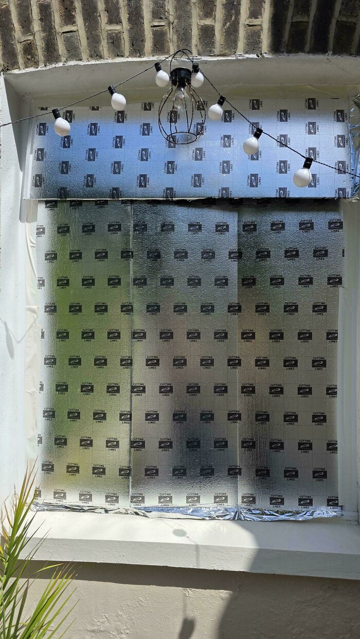 A window covered with reflective insulating foil to block the sun, helping Europeans survive the heatwave.