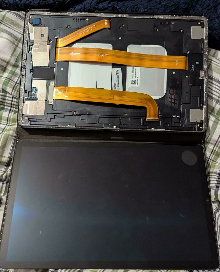 A disassembled tablet with its back cover off, revealing the internal components, damaged by the heatwave, a survival challenge for Europeans.