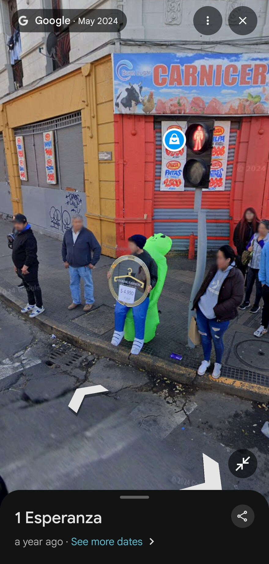 A person in a green alien costume holding a sign on a street in a funny Google Street View photo.