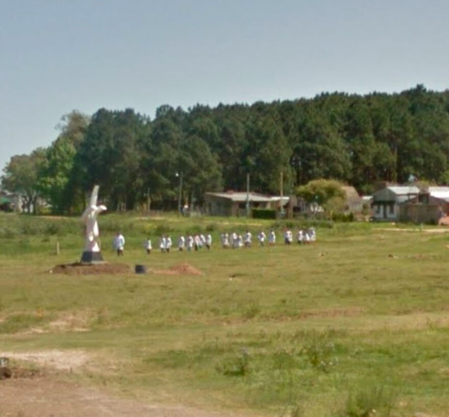 A group of people stand in a field with a statue as captured by Google Street View, showing a bizarre moment.