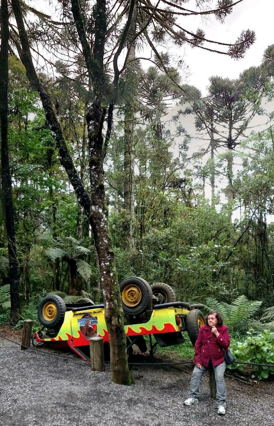 An upside-down jeep is seen in a forest, with a woman looking on, a bizarre sight from Google Street View.