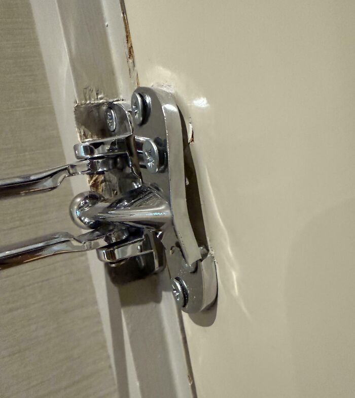 A close-up of a door hinge, bent and damaged, indicating a moment when basic human decency was disregarded, possibly by force or neglect.