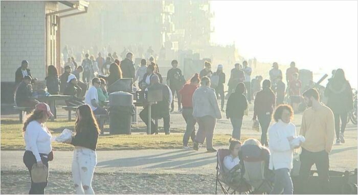 A large group of people gathered outdoors, some seated, some standing, lacking basic human decency.