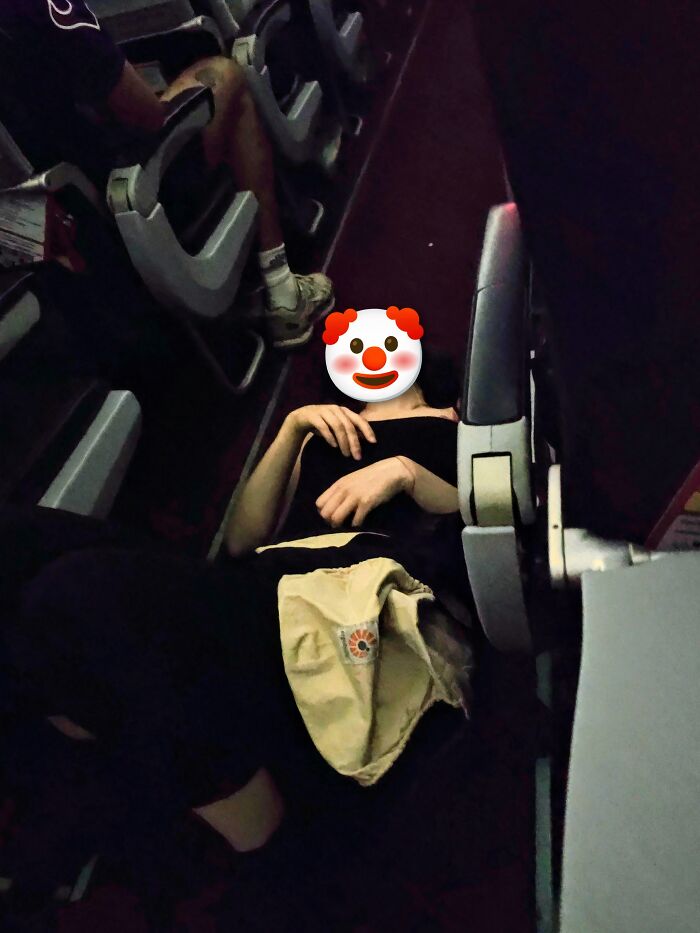 A person lying across multiple seats on an airplane, taking up space and ignoring basic human decency.