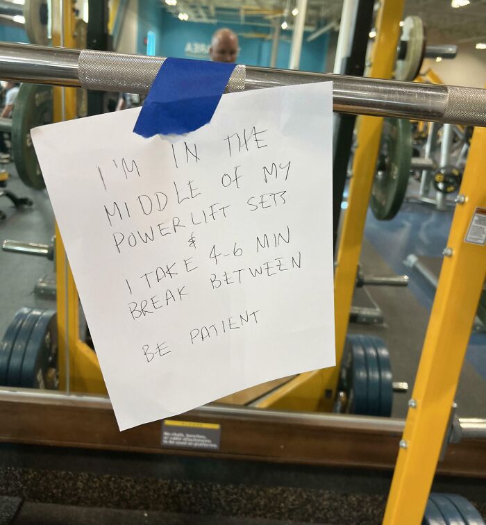 A handwritten note on a powerlift bar at a gym, indicating a need for patience and showing basic human decency.