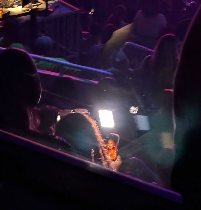 A concert-goer holding up a phone with the flashlight on, illuminating a section of the crowd, showing a lack of basic human decency.