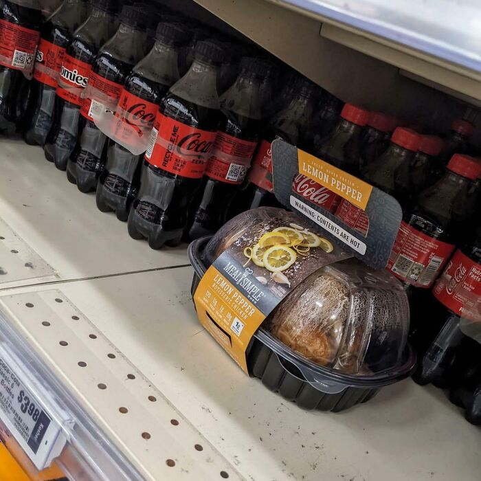 A rotisserie chicken on a grocery shelf, placed among soda bottles, showing a lack of basic human decency.