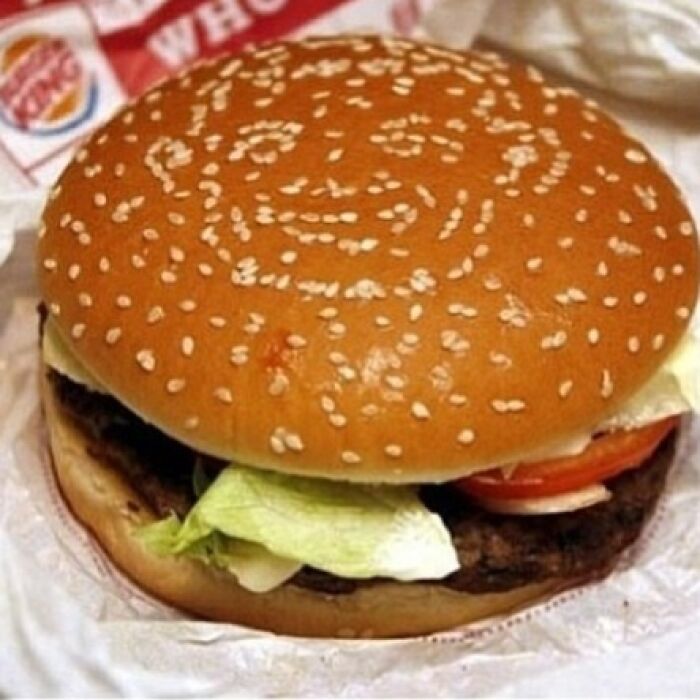 A hamburger with sesame seeds forming a face, making it a curious When You See It picture that short-circuits brains.