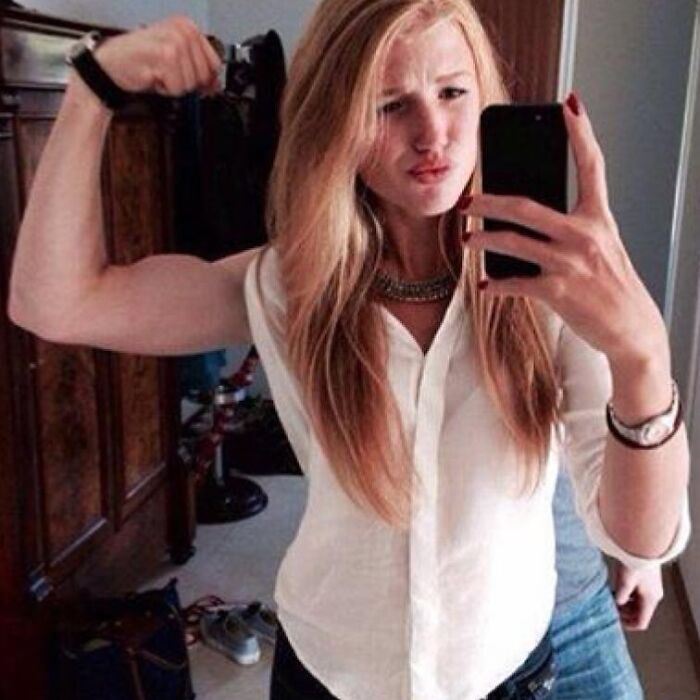 A girl flexing her arm with an unexpected muscular arm in a brain short-circuiting when you see it picture.