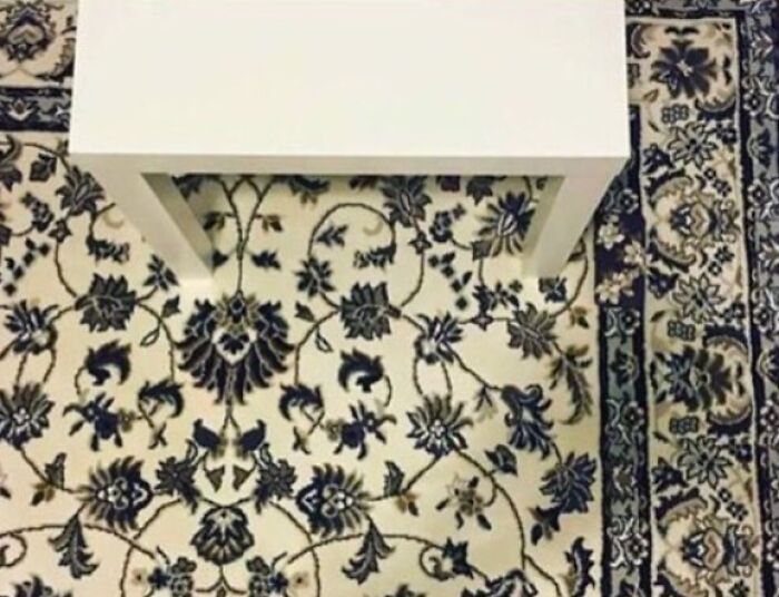 A white table on a floral patterned rug creates a When You See It optical illusion.