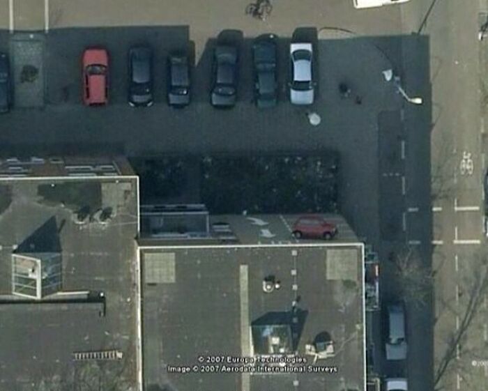 An aerial view of a red car parked on a rooftop, one of many when you see it pictures.