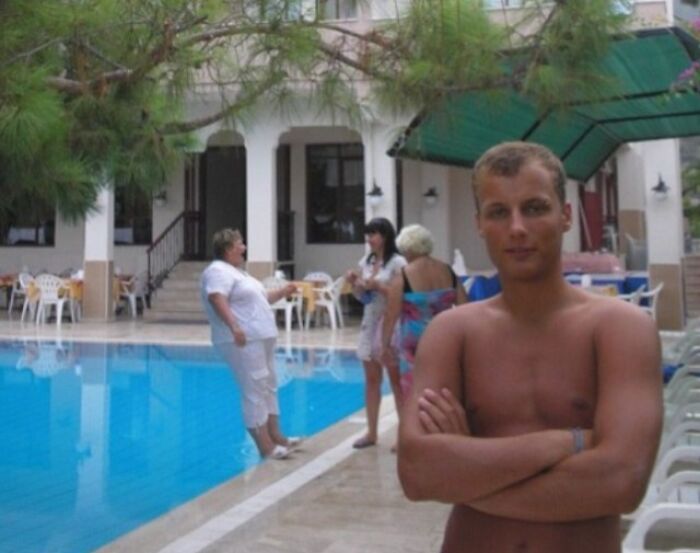 A man posing for a photo while a woman nearly falls into a pool in a funny when you see it picture.