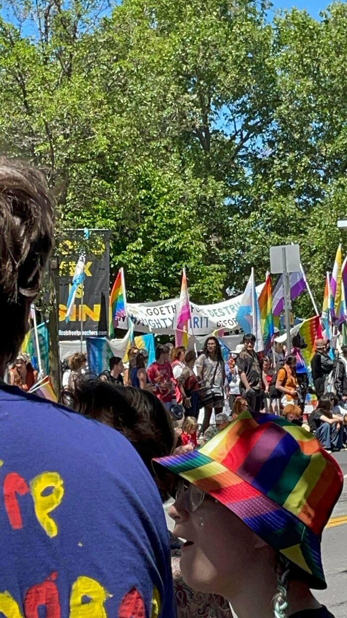 A crowd of people at a parade with rainbow flags, representing chaotic good posts and being a hero in real life.