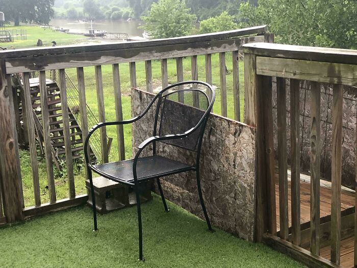A black metal chair on artificial turf, next to a makeshift wooden barrier, showcasing clever solutions.