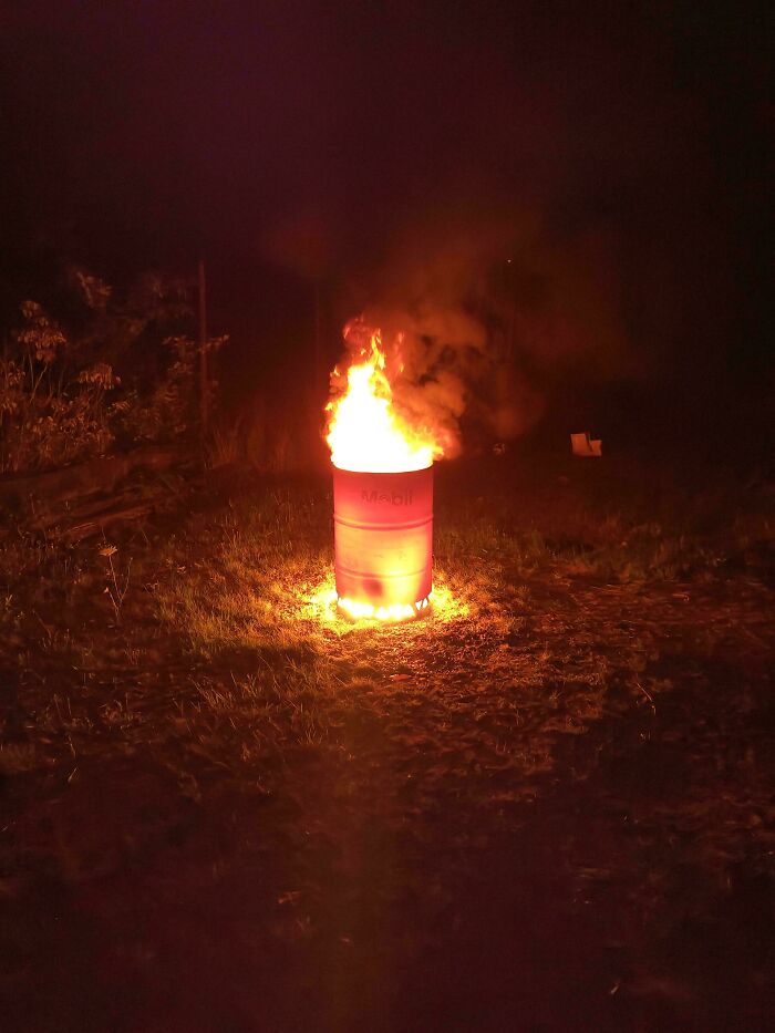 A metal barrel with Mobil branding used as a fire pit, turning random junk into clever solutions.