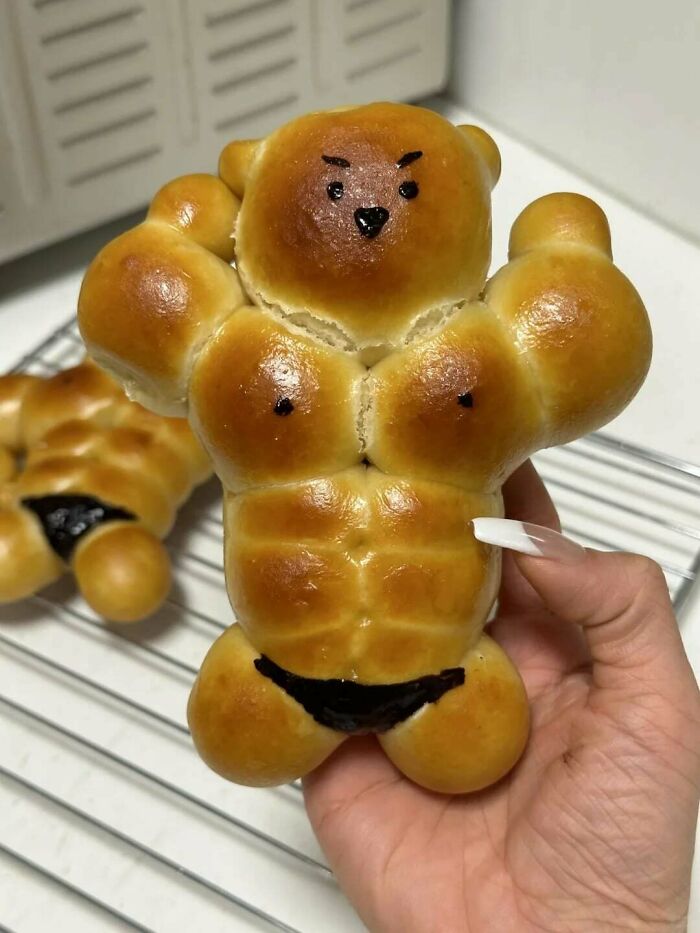 A humorous, muscular bread bear figure, flexing its arms, showcasing creative and delicious treats by bakers.