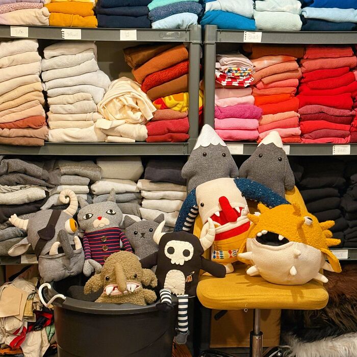 Colorful handmade stuffed toys displayed in front of neatly folded recycled fabrics