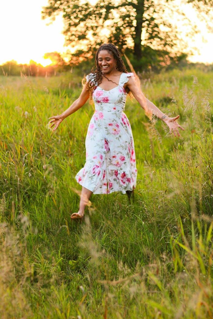 Woman enjoying a sunny field wearing a floral upcycled dress