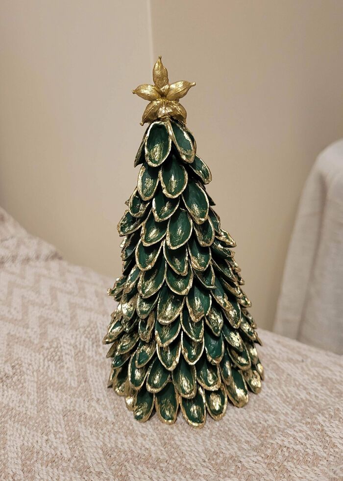 A small, decorative Christmas tree made from pistachio shells painted green and gold, made out of things thrown away.