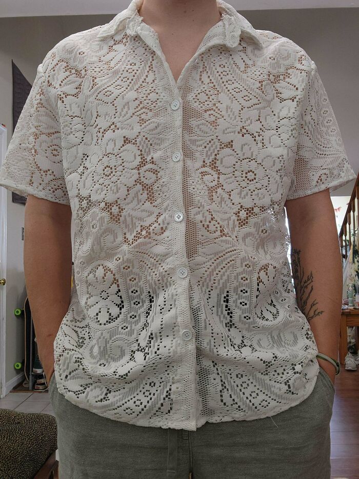 Person wearing a unique white lace short-sleeved shirt, a fashion piece made out of things that would have been thrown away.