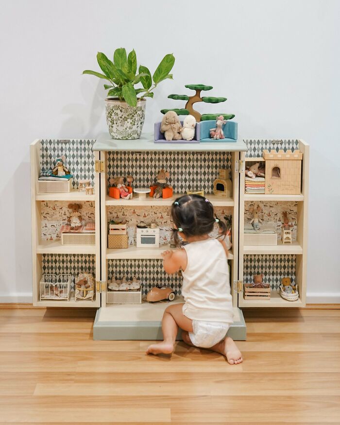 Toddler playing with a dollhouse, an example of things made out of things that would have been thrown away.
