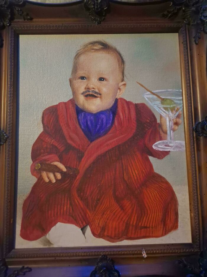A framed painting depicts a baby with a mustache, holding a martini and cigar, made from things that would've been thrown away.