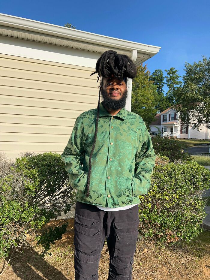 Man in green jacket made out of unexpected things that would've been thrown away