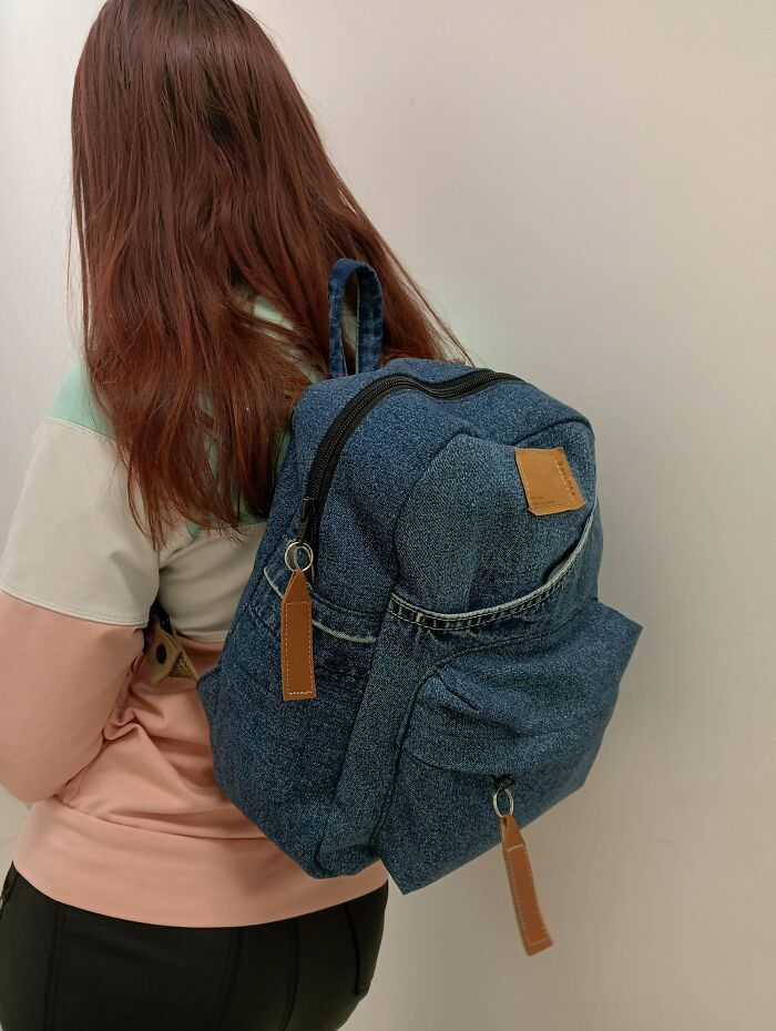 Woman wearing a denim backpack made out of unexpected things that would've been thrown away