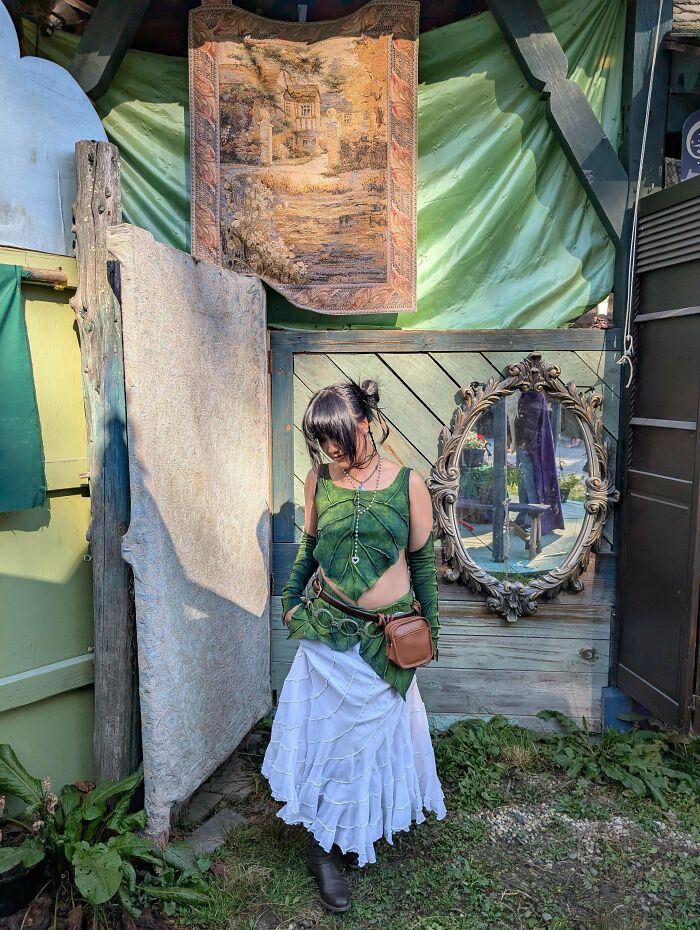 A woman in a leaf-inspired outfit with a flowing white skirt, created from things that would've been thrown away.