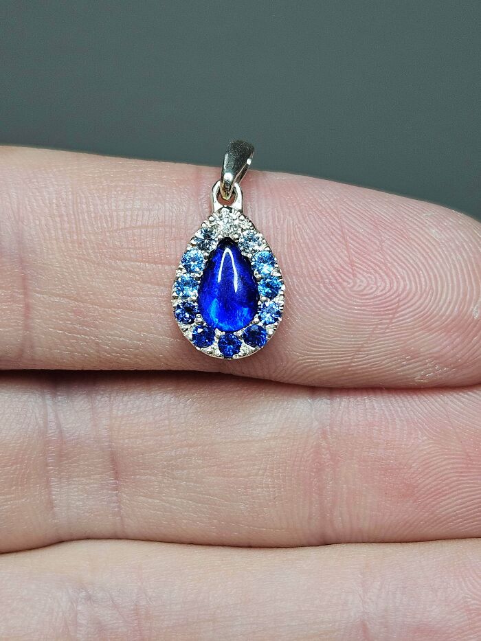 A close-up of a teardrop-shaped blue gemstone pendant, an unexpected thing made from things thrown away.