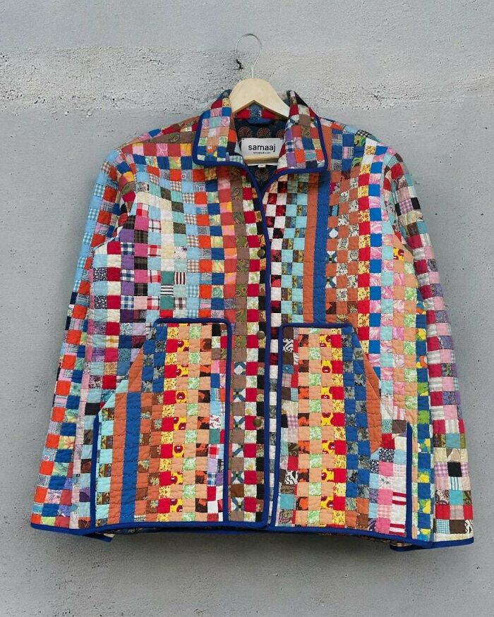 A colorful patchwork jacket made out of things that would've been thrown away, hanging on a wall.