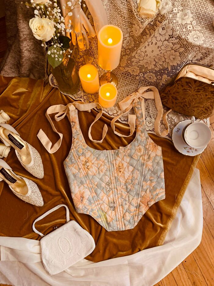 A corset-style top made from things that would have been thrown away, adorned with a floral pattern, displayed with vintage items.