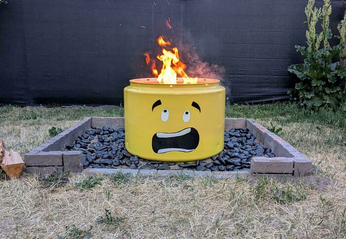 A creative fire pit made out of things that would've been thrown away, resembling a surprised face.