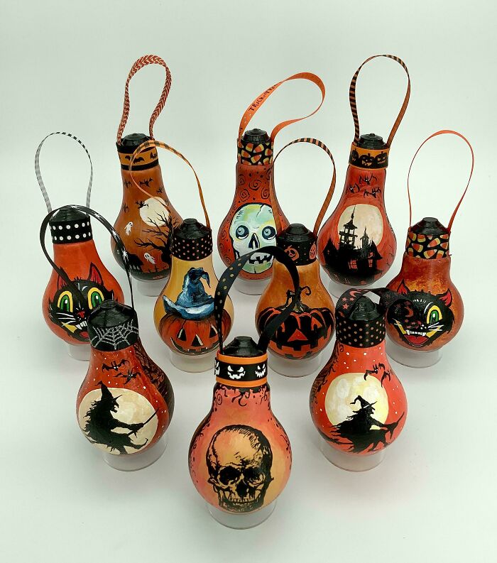 A collection of light bulbs painted with Halloween-themed designs like witches, skulls, and black cats, made out of things that would have been thrown away.