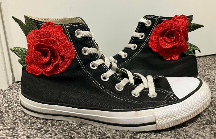 Black high-top sneakers with vibrant red rose appliques on the sides, an unexpected thing made out of things that would've been thrown away.