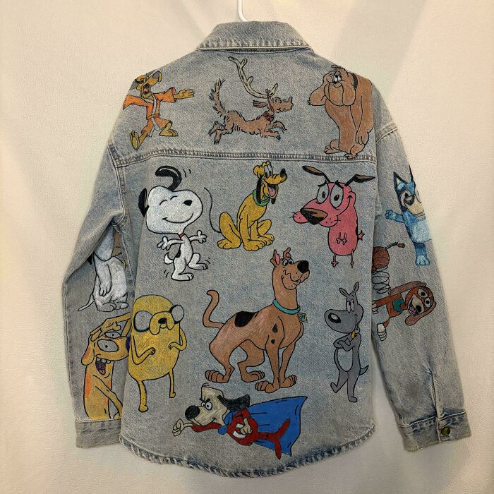 A denim jacket adorned with numerous cartoon dog characters, showcasing things people made out of things that would've been thrown away.