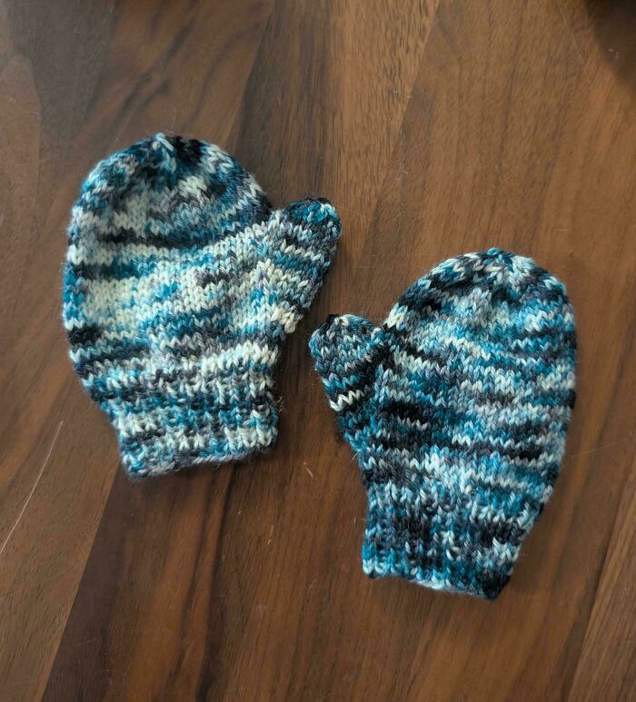 A pair of blue and white knitted mittens on a wooden surface, representing comfort and new beginnings for divorced people.