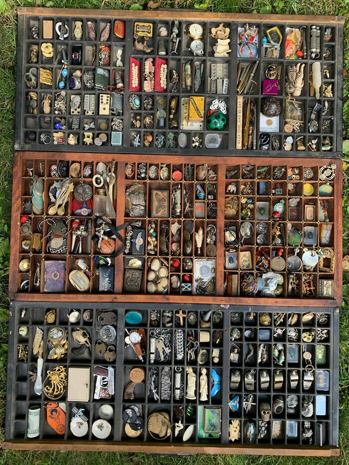 A diverse and fascinating collection of small trinkets, charms, and various items meticulously organized in wooden trays.