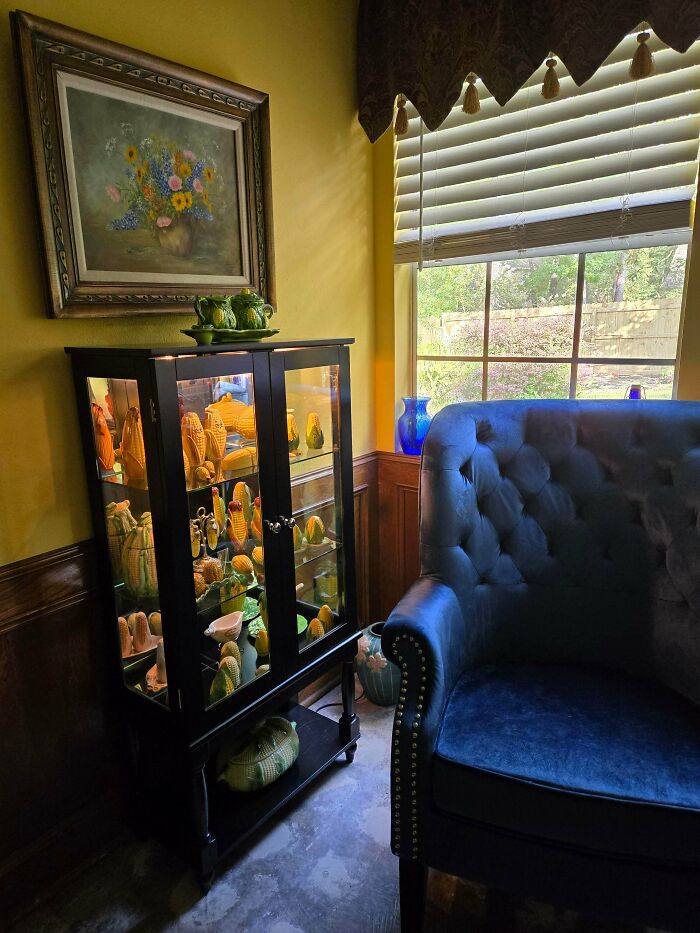 A fascinating collection of ceramic corn and gourds displayed in a lighted curio cabinet.