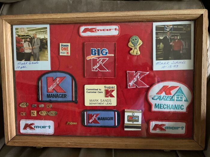 A framed collection of Kmart employee badges, pins, and patches, celebrating years of service.