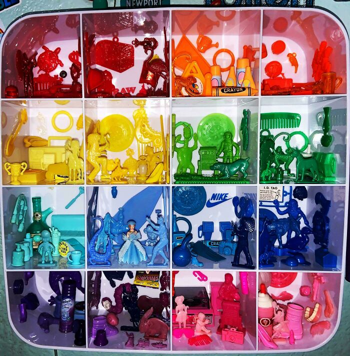 A display case with compartments showing a fascinating collection of small, monochromatic toy figures and objects.