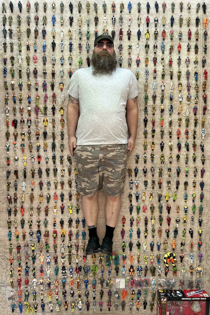 A man lying on a rug surrounded by his extensive collection of miniature action figures.