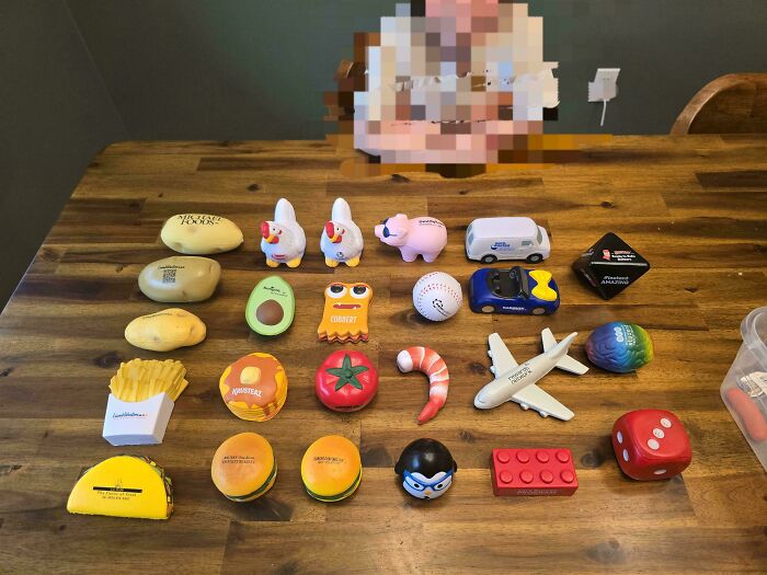An interesting collection of stress balls shaped like food, animals, and other objects on a wooden table.