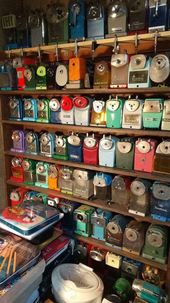 A vast collection of vintage pencil sharpeners neatly arranged on wooden shelves, showcasing various colors and designs.